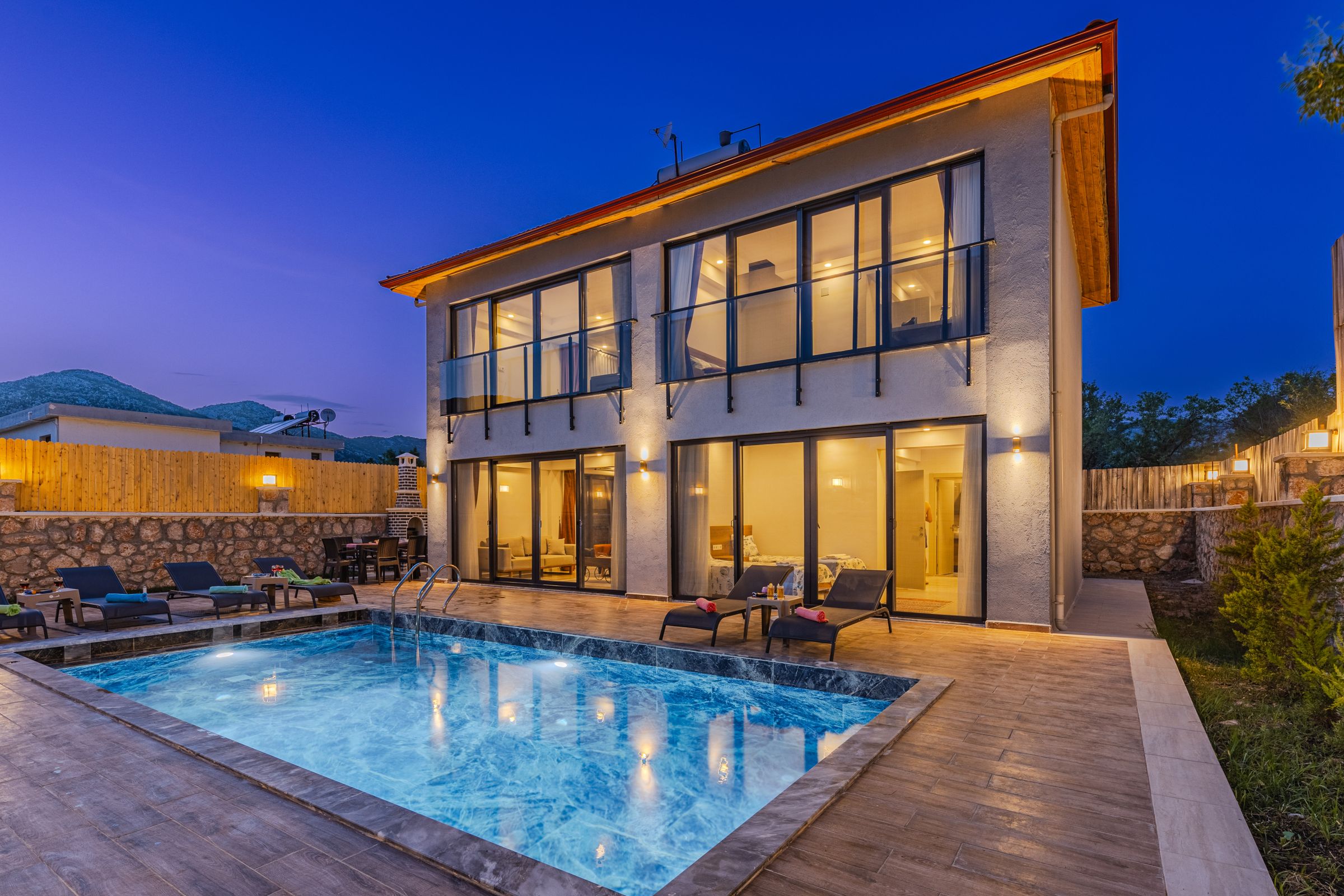 Custom backyard pool glowing lagoon-blue at dusk behind a modern Central Indiana home